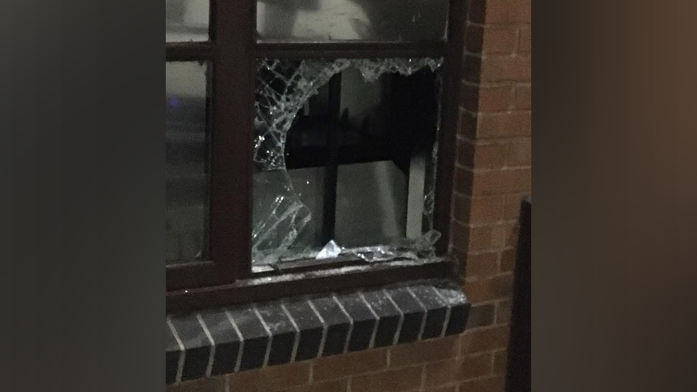 A broken pane of glass in a window. It is set in the brick wall of a property