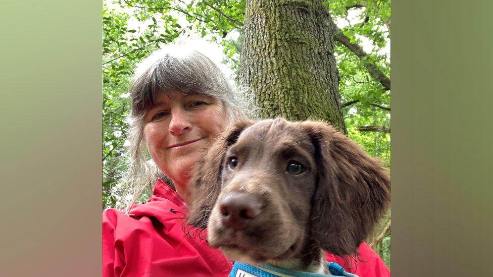 Deborah Flint and her dog beside a tree