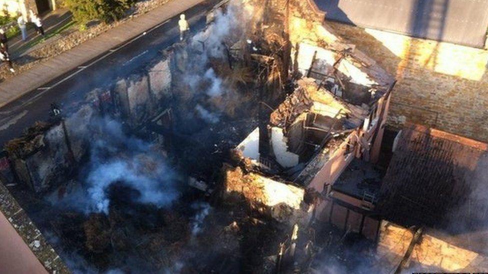 Shell of pub building with smoke seen rising