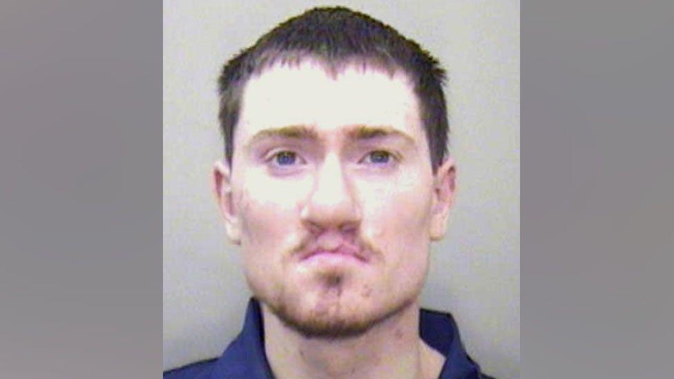 A mugshot of Karl O'Hare who has short brown hair, a goatee beard and a cleft lip, looks into the camera with a blank expression