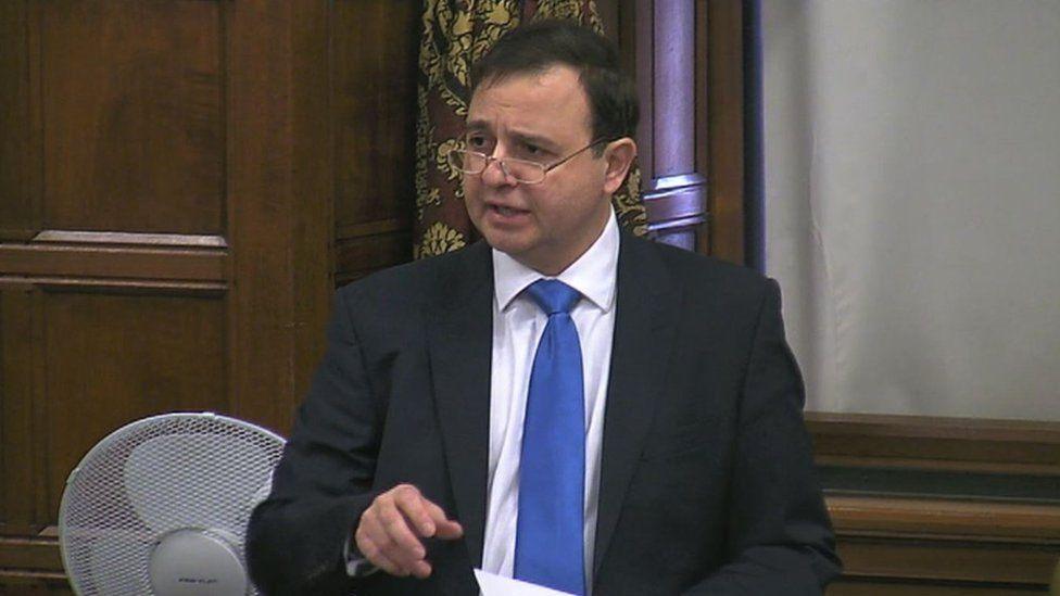 Alberto Costa MP wearing a black suit with a white shirt and blue tie.