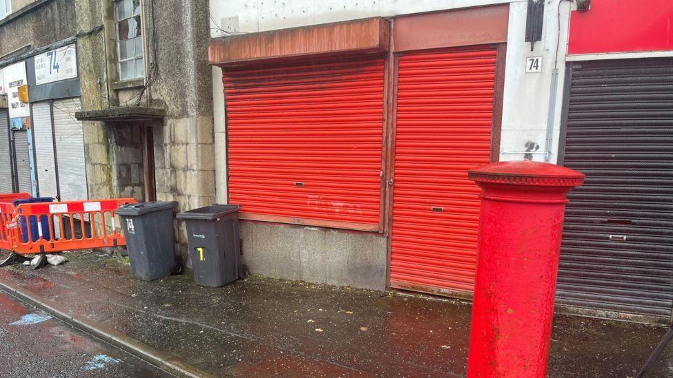 closed shutters on building with red post box outside