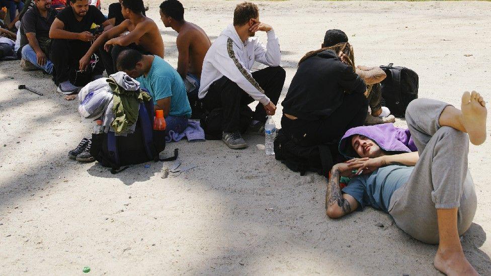 Migrants attempt to cross the US border from Mexico as they are detained by US border patrol officers 