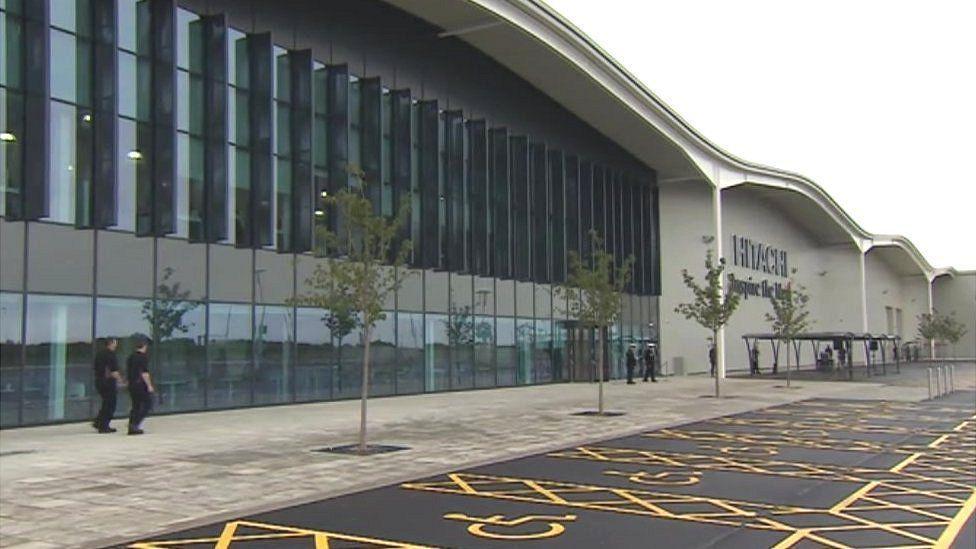 An external view of Hitachi's factory in Newton Aycliffe. Members of staff can be seen walking outside of the building.