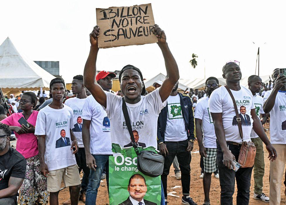 Jean-Louis Billon supporters in white T-shirts supporting him hold up a placard saying in French 'Billon our saviour'.