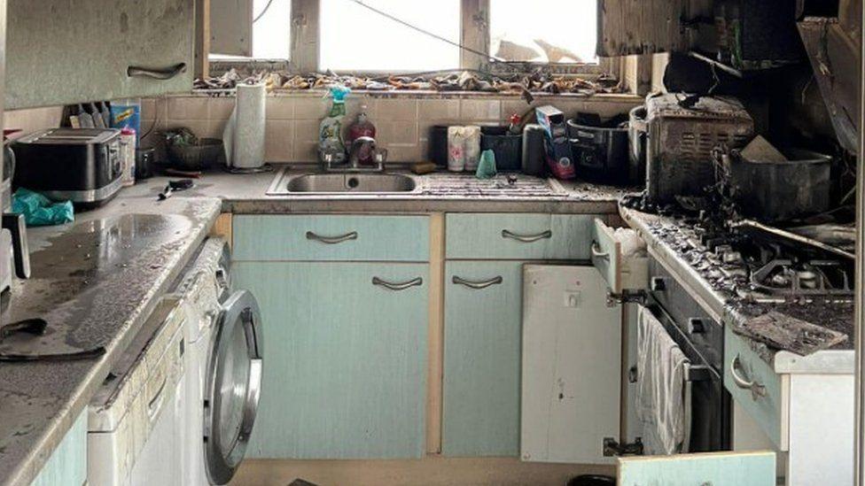 "U" shaped pale blue/green small kitchen charred remains of oven and hob on right