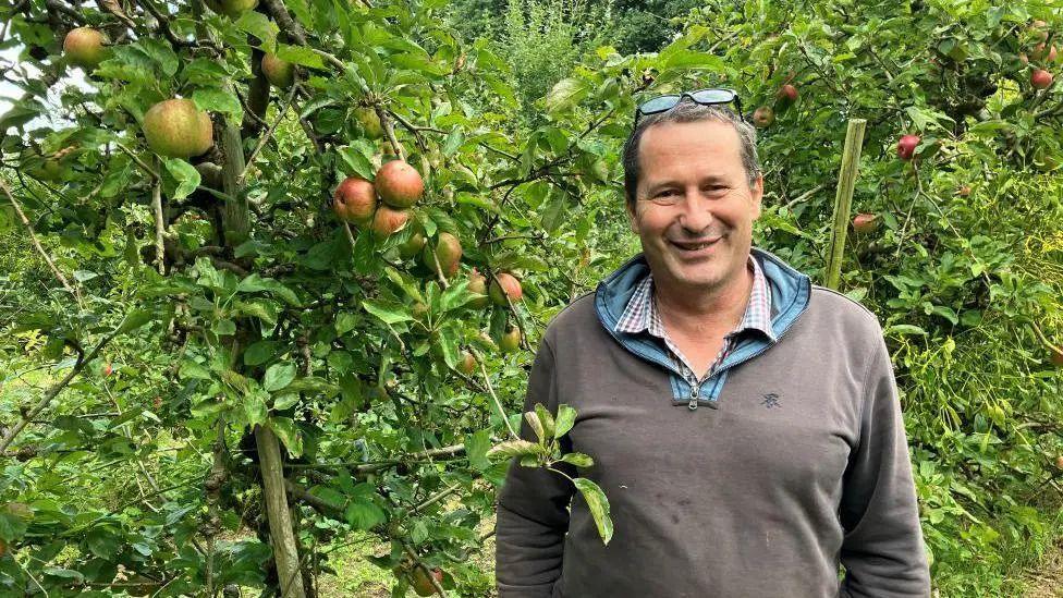 Jonathan Hoskyns stands in front of a fruit tree on his family farm at North Perrott