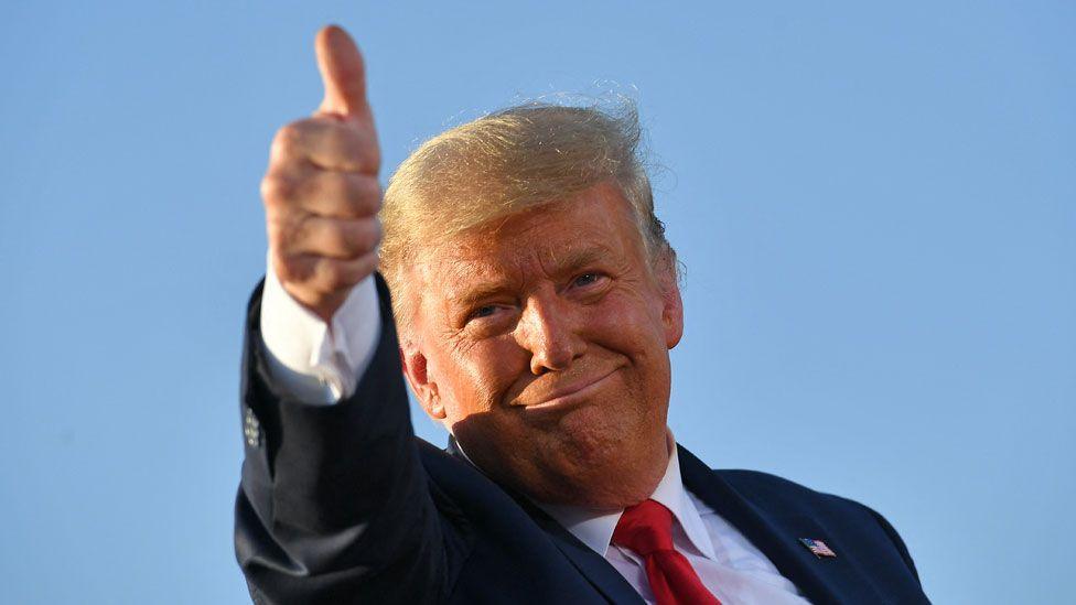 Donald Trump smiling and holding a thumbs-up sign