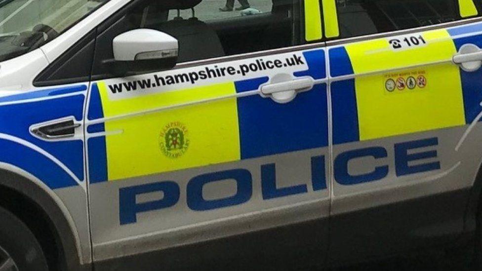 A close-up shot of part of a police car bearing the website address for Hampshire and Isle of Wight Constabulary