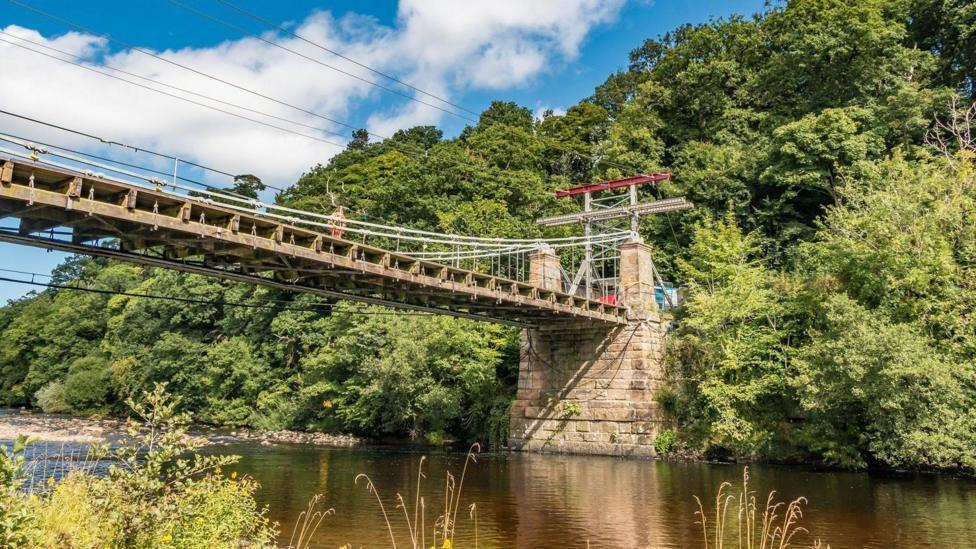 Whorlton Bridge before it was dismantled. Iron chains hold the timber supporting deck in place across the river.