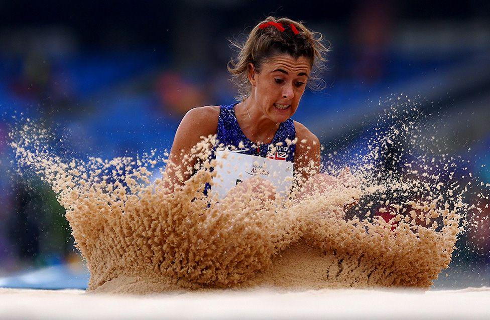 Olivia Breen competes in the Women’s Long Jump T38 Final at the World Para Athletics Championships in New Delhi. She lands in the sandpit wearing a blue competition uniform, creating a dramatic spray of sand.