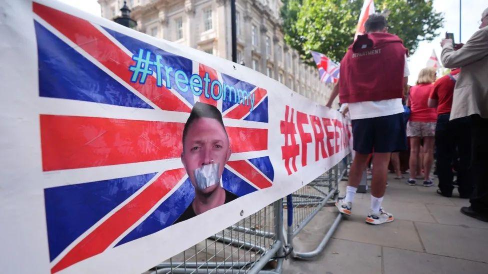 A banner depicting a gagged Tommy Robinson with tape on his mouth. 