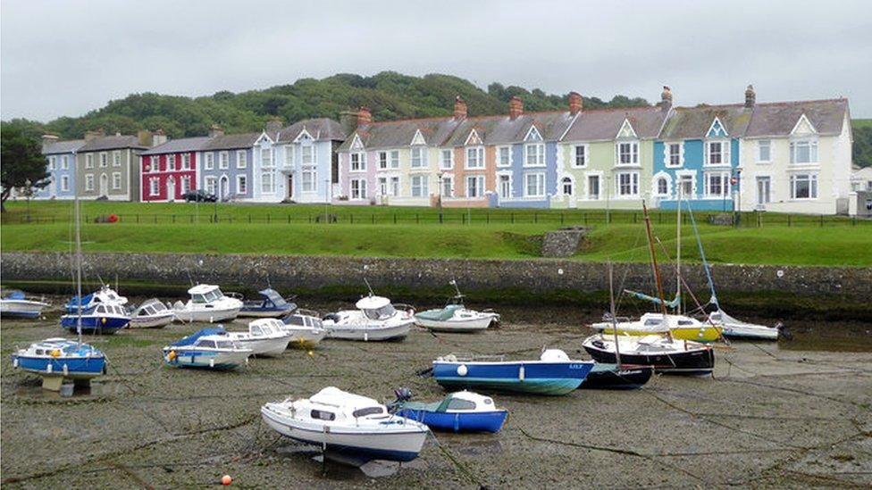 Aberaeron seafront with boats in the harbour and overlooked by a row of terraced homes painted in different colours