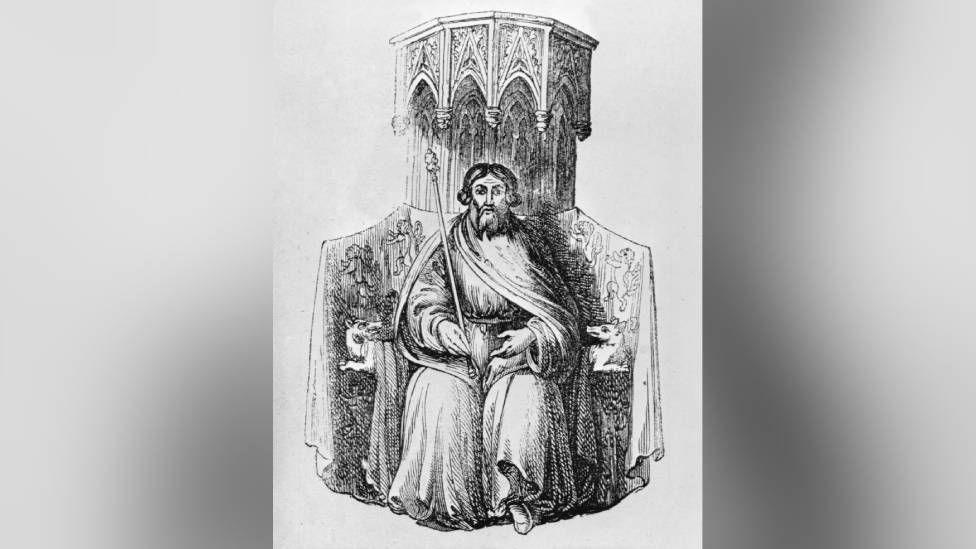 A black and white image of a man with a long beard sat on a throne