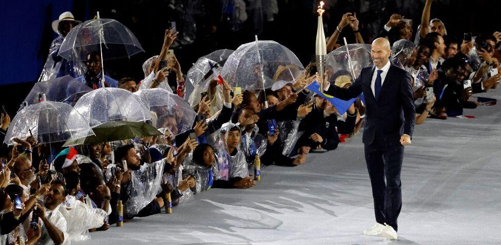 French former football player Zinedine Zidane carries the Olympic torch at the Trocadero during the opening ceremony of the Paris 2024 Olympic Games