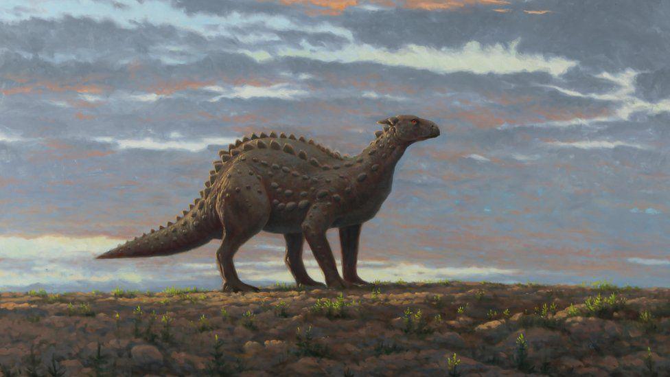 An artist's impression of a Scelidosaurus dinosaur, painted by Julian Frier. It is four legged and has spikes on its back.