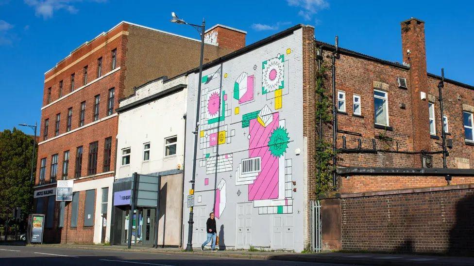 A street view of Future Yard, a building with coloured graffiti and art on the outside of a redbrick building on a street in Liverpool.