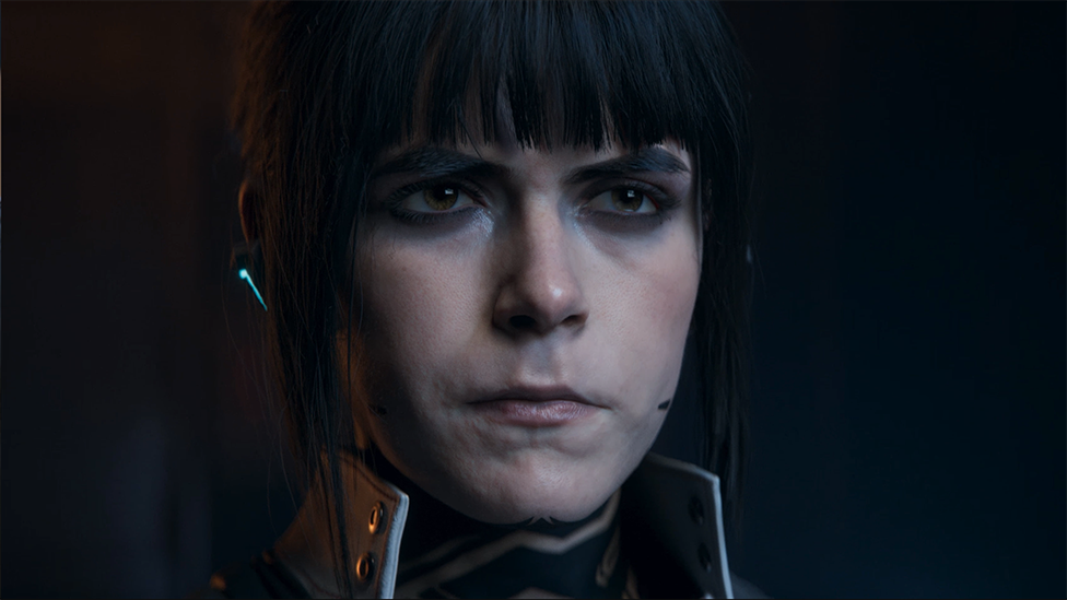 Screenshot shows a photo-realistic rendering of Kiernan Shipka's character, dimly lit, with a stern expression on her face. She wears a high-necked jacket and an earpiece with a microphone stretching towards her mouth.