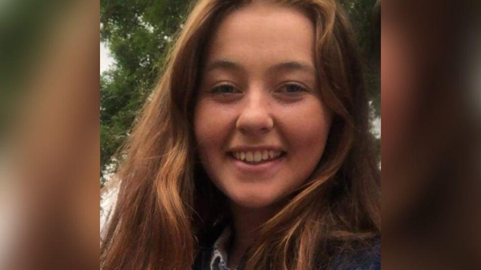 A picture of a young woman with auburn hair smiling