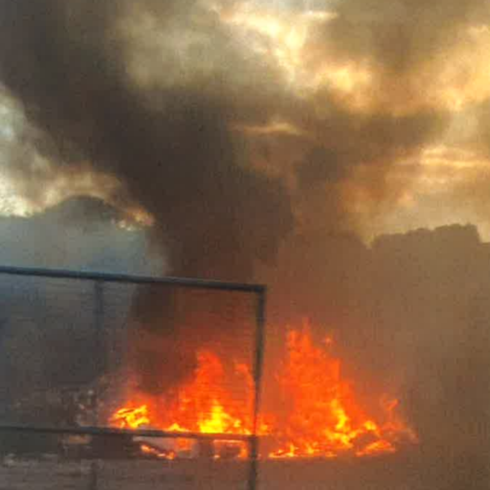 Flames and smoke against a dark hillside.