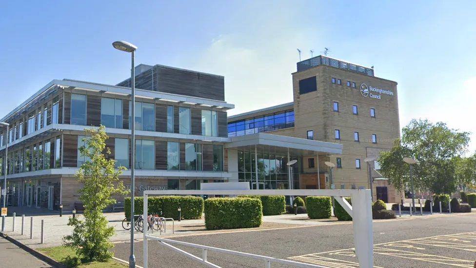 Bucks council offices - 3 storey building with car park in front, edged by box hedges and a white barrier.