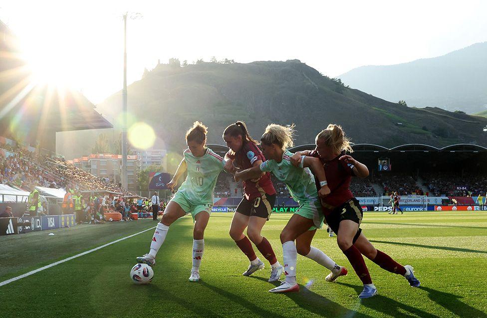 Cristiana Girelli and Emma Severini of Italy battle for possession with Marie Detruyer and Sarah Wijnants of Belgium during the Women's Euro 2025 match in Sion, Switzerland.