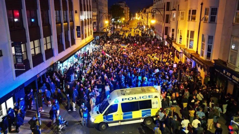 Counter-protesters on the streets on Brighton. Police van in front of the crowd.