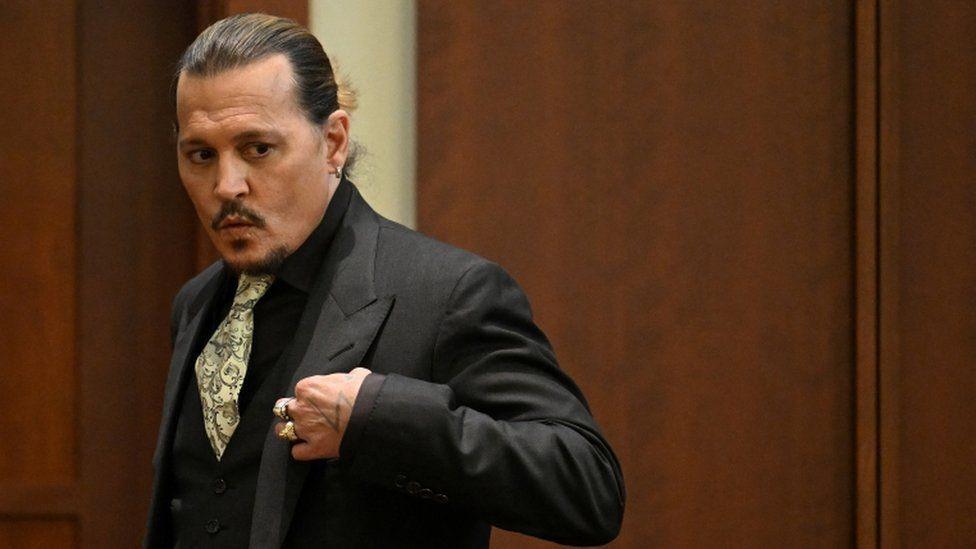 Johnny Depp in court wearing a black suit and shirt and paisley tie