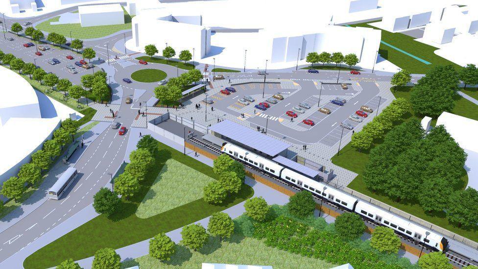 A computer generated aerial image of what the Portishead Rail Station would look like. There are lots of green spaces and trees surrounding the railway line, with a large car park and green roundabout