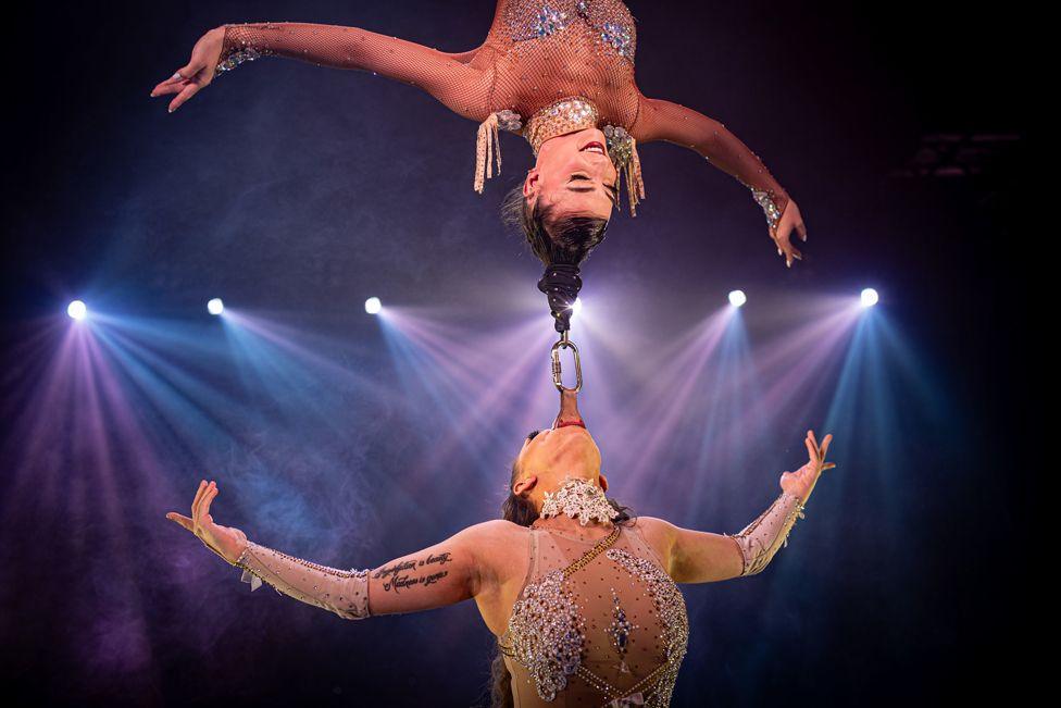 A pair of Circus Vegas aerial performers hang from their hair and teeth as they rehearse ahead their UK tour appearance on Durdham Downs in Bristol. 3 October, 2024. 