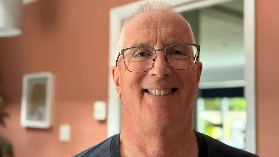 A headshot image of Robin Sainty. He is wearing glasses and smiling while looking into the camera.