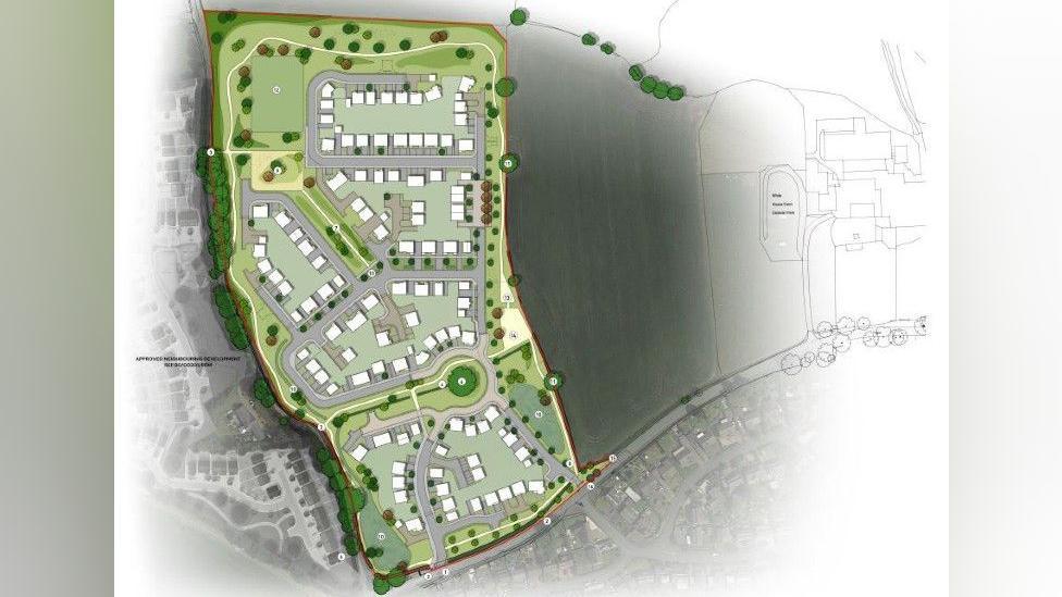 An aerial diagram of the housing development. It is on green lane, with trees and bushes surrounding it. There are 150 white blocks to represent houses, and roads and fields surrounding the site