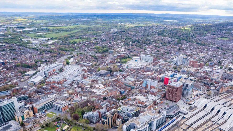 A drone shot of Reading city centre - with a train station and tower buildings particularly prominent.