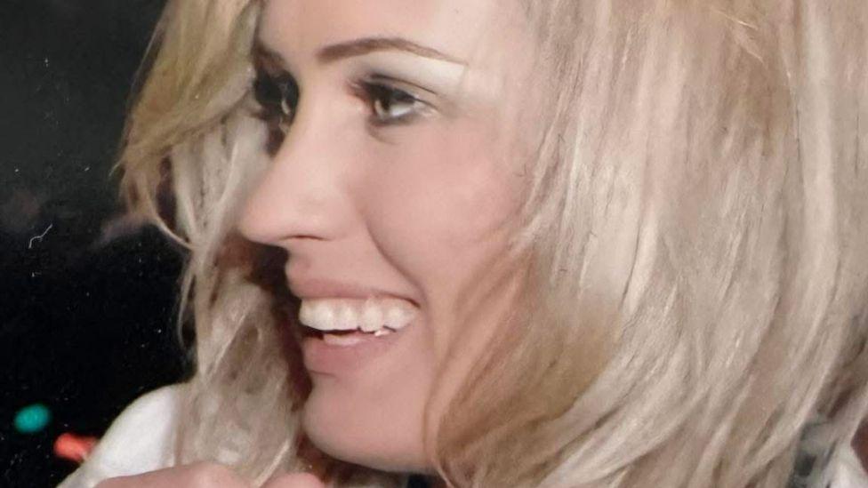 A close-up of Belinda Taylor, who in this pictures has fair hair. She is also in a blue top and pale jacket.