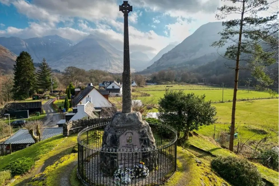 The Glencoe massacre memorial - a Celtic cross mounted on a rock - stands in the village with imposing mountains in the distance.