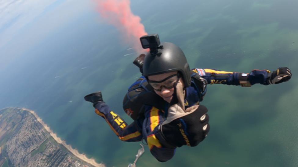 A member of the Tigers Army Parachute Display Team gives a thumbs up to the camera mid-air