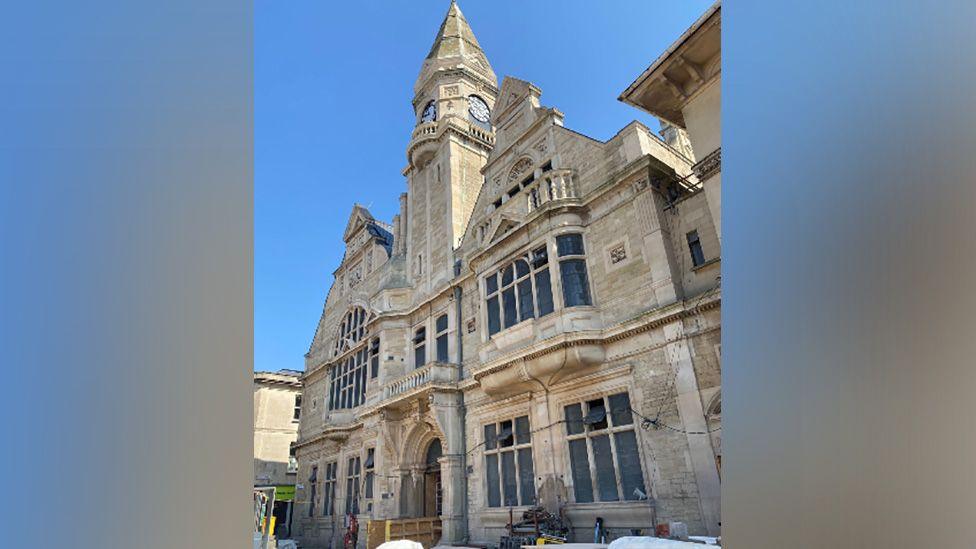 Front of a grand limestone building with clock tower