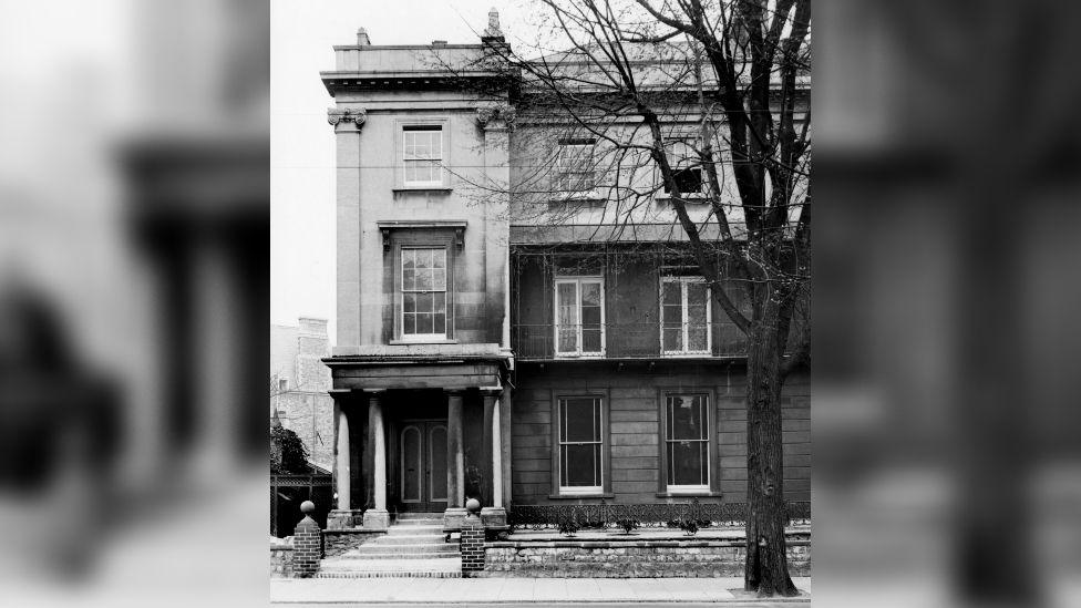 A black and white image of the former entrance to BBC Bristol on Whiteladies Road. It is a large stone building with sash windows and pillars outside.