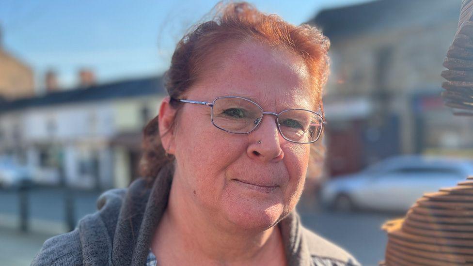 Close-up image of Cath Holmes, wearing glasses and smiling