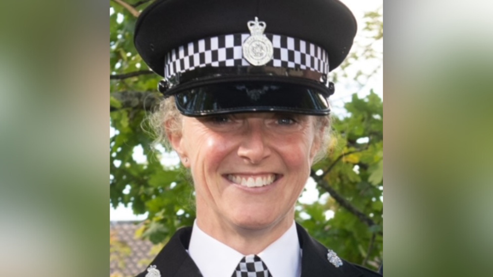 A headshot of a smiling woman in a black and white police uniform.