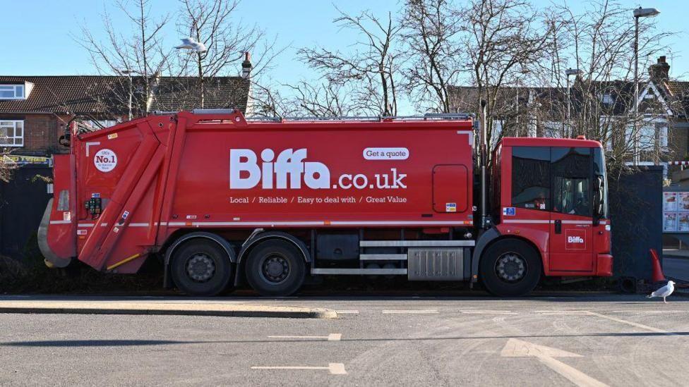 A large red bin lorry bearing the logo of waste firm BIFFA