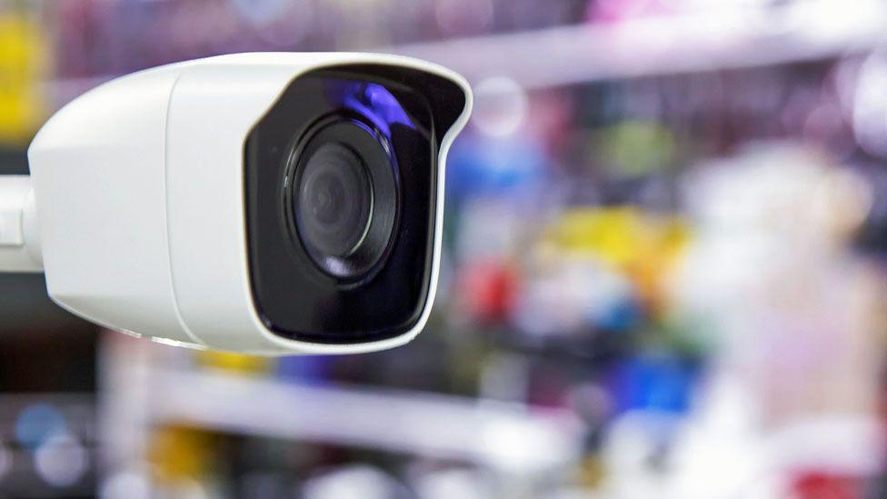 Close-up of a CCTV with a blurred background of goods on shop shelves