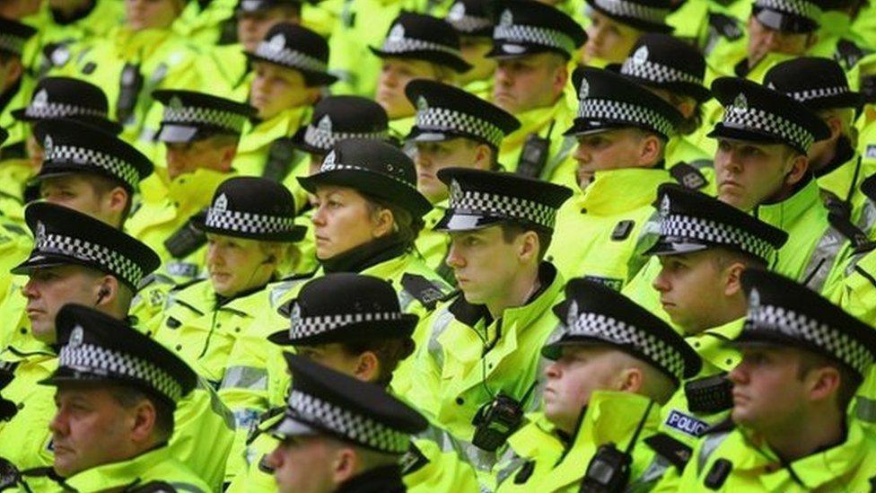 Tight close up of police officers wearing hats and hi-vis jackets.
