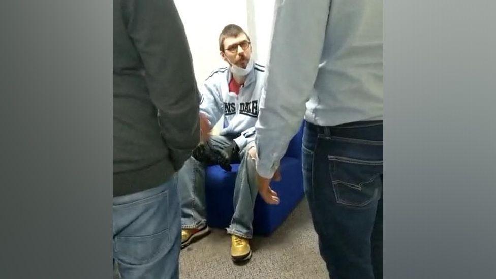 Cavan Medlock seated and surrounded by staff seen in the foreground