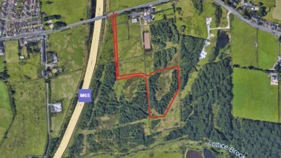 An aerial view of the site for the proposed Stanhill Road battery farm, showing fields to the right of the M65, with a road and piece of woodland edged in red