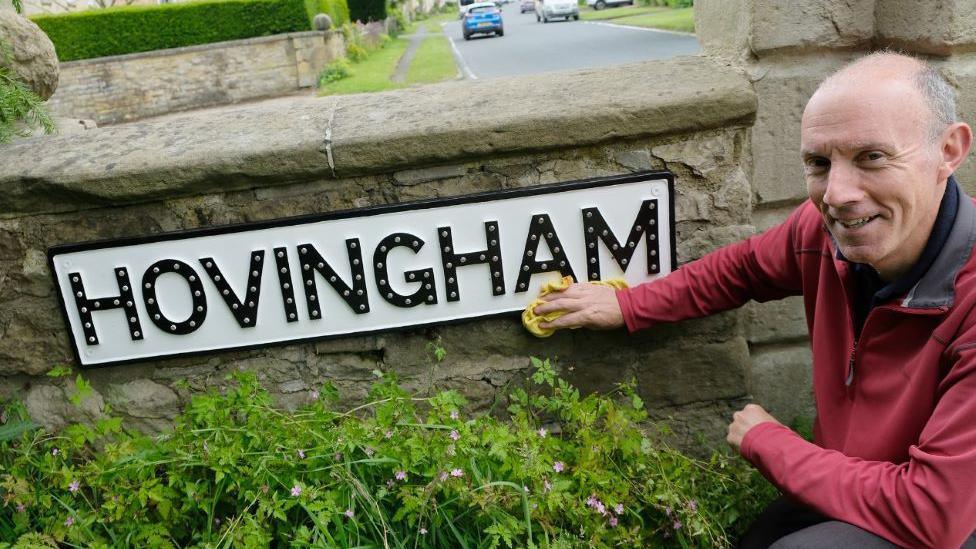 Man cleaning road direction sign