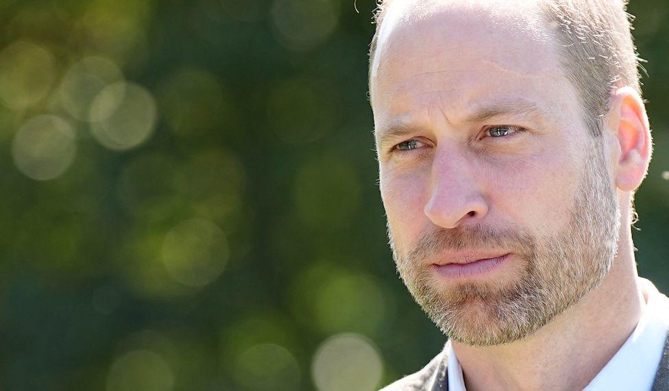 Close-up of Prince William, Prince of Wales, looking earnest, pictured against a background of green foliage
