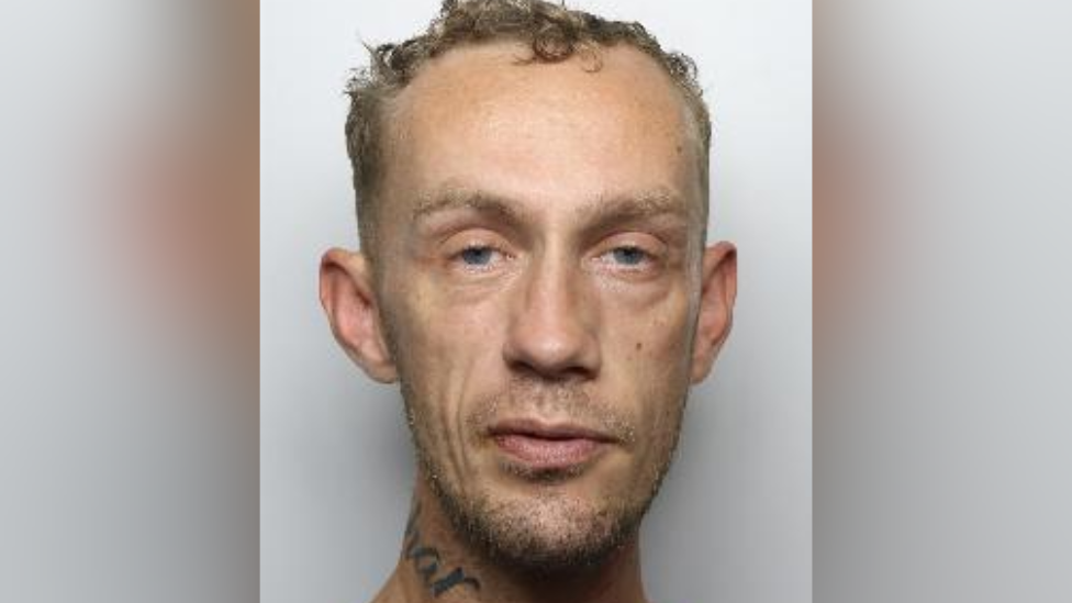 Custody picture of Andrew McMinn, a man with short curly hair and a tattoo on his neck.