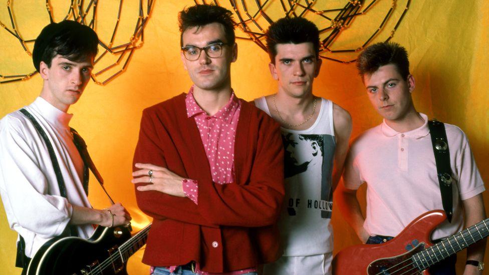 The Smiths' guitarist Johnny Marr, in a white shirt, singer Morrissey, in glasses and a pink and white spotted shirt and a red cardigan, drummer Mike Joyce, in a white vest, and bassist Andy Rourke, in a pink polo shirt pose for a portrait before their first show in Detroit during the 1985 Meat Is Murder Tour 