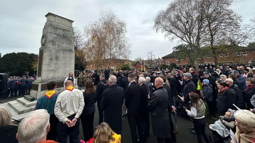 Crowds of residents, veterans and dignitaries surround Goole's Cenotaph, a tall white war memorial, during 2024's Remembrance Sunday ceremony. 